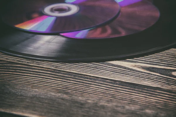 Старые и морденские звуковые диски на деревянном столе — стоковое фото