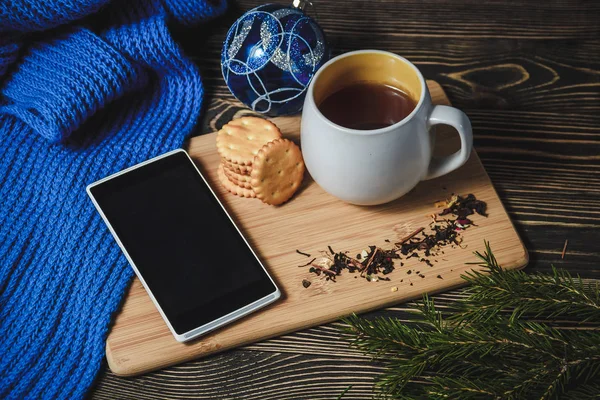 Tea és smartphone közepén aranyos karácsonyi dekoráció — Stock Fotó