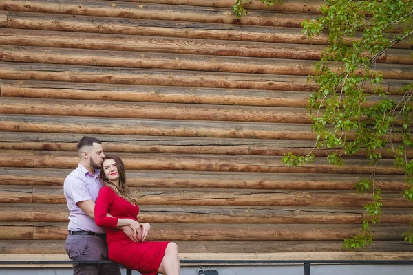 Šťastná rodina těhotná žena a muž stojící před dřevěné stěny — Stock fotografie