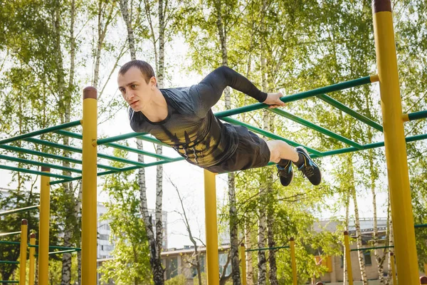 Hombre de fitness en el bar. Hacer ejercicio al aire libre en el parque. Entrenamiento callejero . —  Fotos de Stock