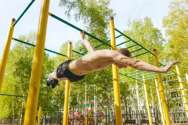 Hombre de fitness en el bar. Hacer ejercicio al aire libre en el parque. Entrenamiento callejero . —  Fotos de Stock