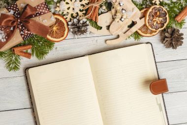 Noel süsler ve hafif ahşap masa üstünde açık bir boş defter