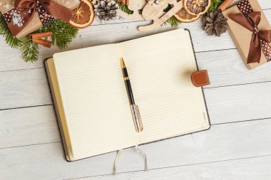 Noel süsler ve hafif ahşap masa üstünde açık bir boş defter