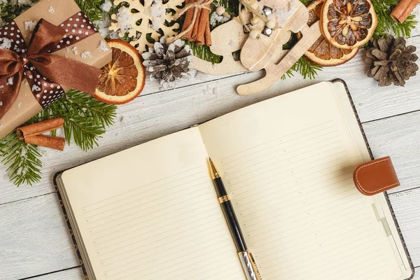 Noel süsler ve hafif ahşap masa üstünde açık bir boş defter