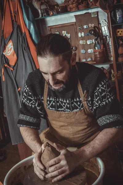 Adult male potter master mashing the clay