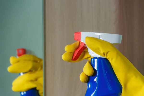 Mano femenina en el espejo de limpieza de guantes amarillos con limpiador de aerosol. en Botella Azul, Limpieza de la Casa, Concepto de Limpieza de Primavera . — Foto de Stock