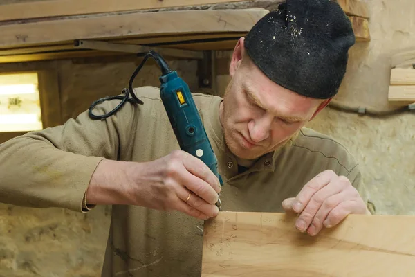 Closeup Carpenter v čepici a svetr broušení prkno v dílně. Průmyslová výroba koncept. — Stock fotografie