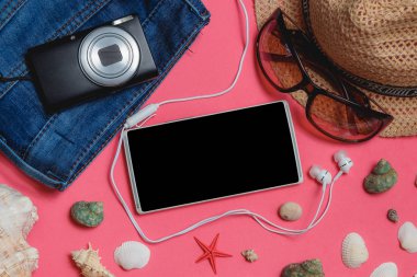 Smartphone, elbiseler, güneş gözlüğü, fotoğraf kamera, pembe bir arka plan üzerinde kahverengi şapka. En iyi görünümü seyahat kavramı alay kadar.