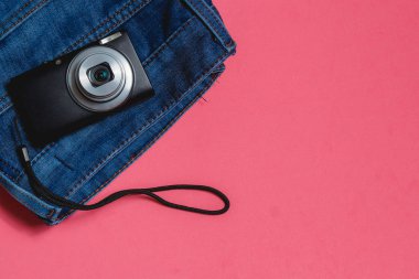 Elbiseler, pembe bir arka plan üzerinde fotoğraf makinesi. Üstten Görünüm seyahat kavramı ile boşaltmak.