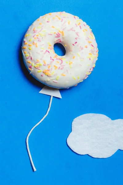 Donut på blå, kreativ mat Minimalism, Donut i form av ballong i himlen med moln, ovanifrån med kopia utrymme, tonas — Stockfoto