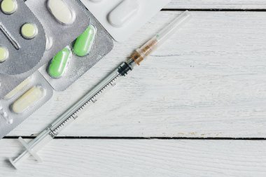 Çeşitli tablet ayarla, kapsüller içinde..... kabarcıklar, şırınga kopya alanı ile beyaz ahşap zemin üzerinde. Tıp kavramı.