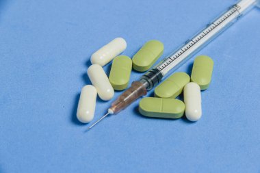 Mavi arka plan üzerinde çeşitli tablet, kapsül, şırınga kümesi. Tıp kavramı.