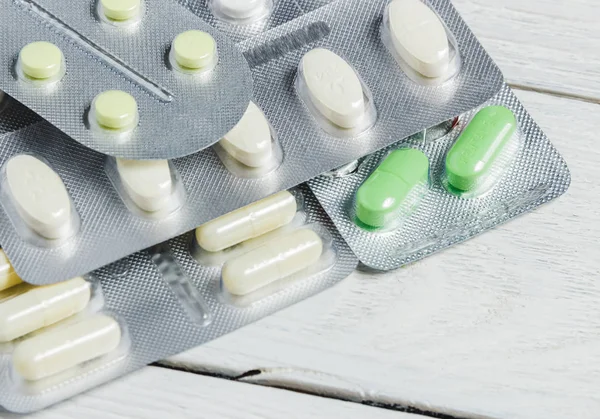 Set aus verschiedenen Tabletten und Kapseln in Blasen auf weißem Holzhintergrund mit Kopierraum. Medizinkonzept. — Stockfoto