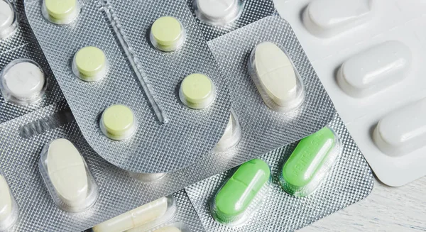 Set aus verschiedenen Tabletten und Kapseln in Blasen auf weißem Holzgrund. Medizinkonzept. — Stockfoto