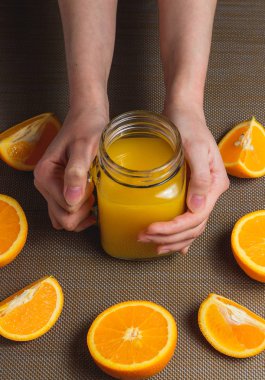 Portakal suyu ile dilimlenmiş portakal koyu arka plan üzerinde tutan el. Sağlıklı kavramı.