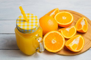 Beyaz ahşap zemin üzerine dilimlenmiş portakal ve meyve suyu iç. Sağlıklı kavramı.