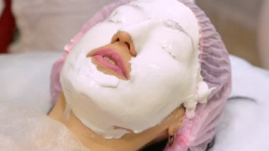 Güzellik salonundaki genç kadın aljinat maskesi yapıyor. Nemlendirici, yumuşatıcı, yenilenen maske uygulaması. Yüzdeki yenilenme işlemi Darsonval 'dan önce. Tıbbi güzellik ekipmanları.