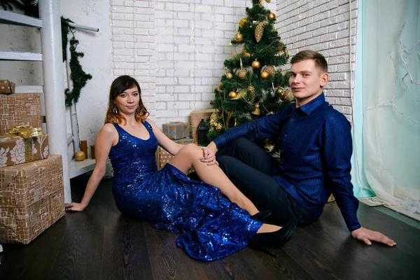 Young ordinary family of two. Young husband and wife near christmas tree. Happy young hetero couple decorate christmas tree at home. — Stock Photo, Image