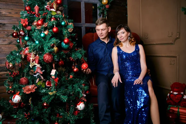 Jonge gewone familie van twee. Jonge man en vrouw in de buurt van kerstboom. Gelukkig jong hetero paar versieren kerstboom thuis. — Stockfoto