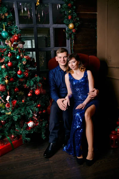 Young ordinary family of two. Young husband and wife near christmas tree. Happy young hetero couple decorate christmas tree at home. — Stock Photo, Image