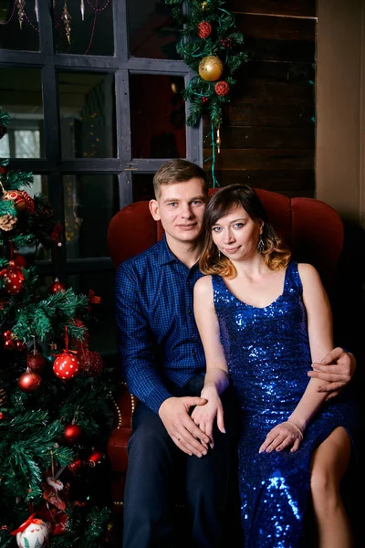 Young ordinary family of two. Young husband and wife near christmas tree. Happy young hetero couple decorate christmas tree at home. — 스톡 사진