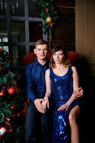 Young ordinary family of two. Young husband and wife near christmas tree. Happy young hetero couple decorate christmas tree at home. — Stock Photo, Image