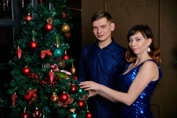Jonge gewone familie van twee. Jonge man en vrouw in de buurt van kerstboom. Gelukkig jong hetero paar versieren kerstboom thuis. — Stockfoto