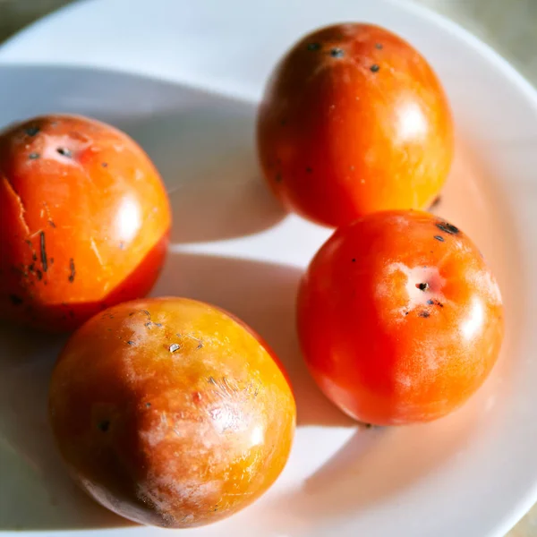 Fruits kaki sur une assiette blanche vue rapprochée du dessus . — Photo
