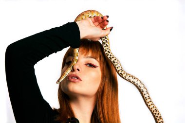 Siyah elbiseli ve yılanlı güzel bir kadın. Mükemmel makyajlı kızıl model kız..