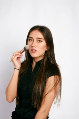 Profesyonel makyaj sanatçısı beyaz arka planda reklam için makyaj fırçası ve makyaj ürünleriyle poz veriyor. Tasarım için kopyalama.