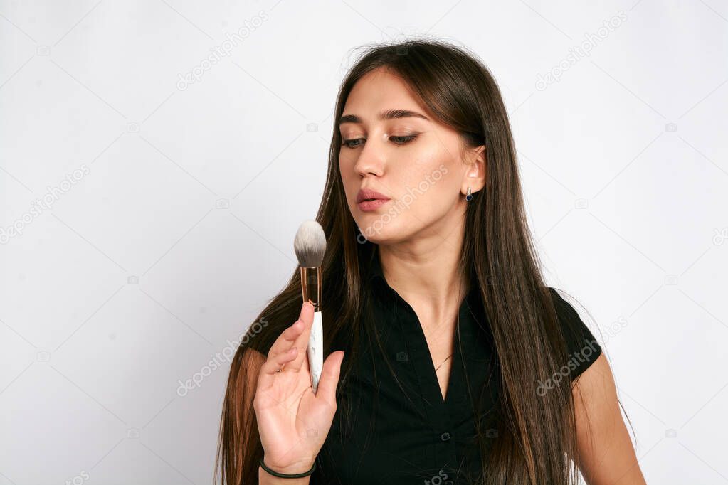 Professional makeup artist poses with the makeup brush and makeup products for advertising on white background. Copyspase for design.