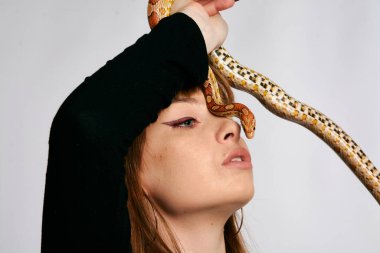 Siyah elbiseli ve yılanlı güzel bir kadın. Mükemmel makyajlı kızıl model kız. Üst düzey rötuş. Beyaz arka plan. Taze ciltli genç bir kadın. Etrafında yılan olan bir kadın..