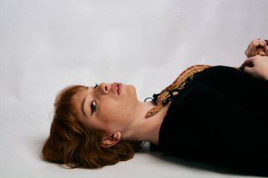 Siyah elbiseli ve yılanlı güzel bir kadın. Mükemmel makyajlı kızıl model kız. Üst düzey rötuş. Beyaz arka plan. Taze ciltli genç bir kadın. Etrafında yılan olan bir kadın..