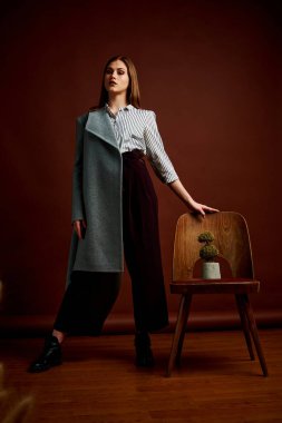 Genç bağımsız kadının mininalizm stili klasik stüdyo fotoğraf seti. Klasik takım elbiseli, siyah ayakkabılı ve gri ceketli güzel bir bayan. Klasik sandalye. Kadın kıyafetleri. Şık kıyafetler..