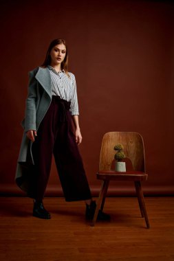 Genç bağımsız kadının mininalizm stili klasik stüdyo fotoğraf seti. Klasik takım elbiseli, siyah ayakkabılı ve gri ceketli güzel bir bayan. Klasik sandalye. Kadın kıyafetleri. Şık kıyafetler..