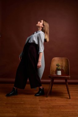 Genç bağımsız kadının mininalizm stili klasik stüdyo fotoğraf seti. Klasik takım elbiseli, siyah ayakkabılı ve gri ceketli güzel bir bayan. Klasik sandalye. Kadın kıyafetleri. Şık kıyafetler..