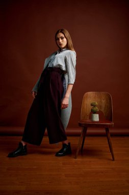 Genç bağımsız kadının mininalizm stili klasik stüdyo fotoğraf seti. Klasik takım elbiseli, siyah ayakkabılı ve gri ceketli güzel bir bayan. Klasik sandalye. Kadın kıyafetleri. Şık kıyafetler..