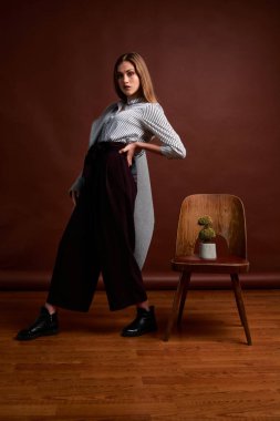 Genç bağımsız kadının mininalizm stili klasik stüdyo fotoğraf seti. Klasik takım elbiseli, siyah ayakkabılı ve gri ceketli güzel bir bayan. Klasik sandalye. Kadın kıyafetleri. Şık kıyafetler..