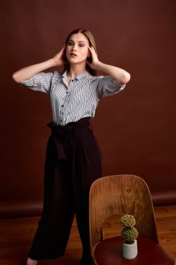 Genç bağımsız kadının mininalizm stili klasik stüdyo fotoğraf seti. Klasik takım elbiseli, siyah ayakkabılı ve gri ceketli güzel bir bayan. Klasik sandalye. Kadın kıyafetleri. Şık kıyafetler..