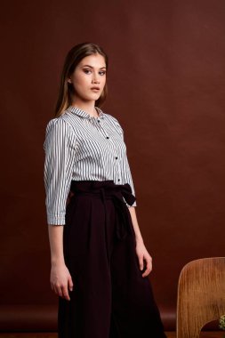 Genç bağımsız kadının mininalizm stili klasik stüdyo fotoğraf seti. Klasik takım elbiseli, siyah ayakkabılı ve gri ceketli güzel bir bayan. Klasik sandalye. Kadın kıyafetleri. Şık kıyafetler..