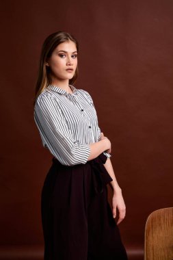 Genç bağımsız kadının mininalizm stili klasik stüdyo fotoğraf seti. Klasik takım elbiseli, siyah ayakkabılı ve gri ceketli güzel bir bayan. Klasik sandalye. Kadın kıyafetleri. Şık kıyafetler..