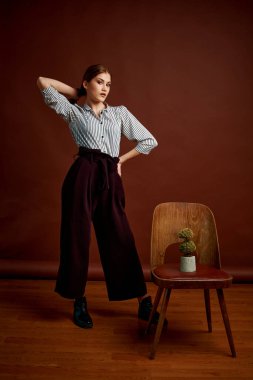Genç bağımsız kadının mininalizm stili klasik stüdyo fotoğraf seti. Klasik takım elbiseli, siyah ayakkabılı ve gri ceketli güzel bir bayan. Klasik sandalye. Kadın kıyafetleri. Şık kıyafetler..