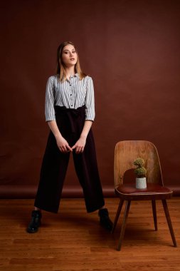 Genç bağımsız kadının mininalizm stili klasik stüdyo fotoğraf seti. Klasik takım elbiseli, siyah ayakkabılı ve gri ceketli güzel bir bayan. Klasik sandalye. Kadın kıyafetleri. Şık kıyafetler..
