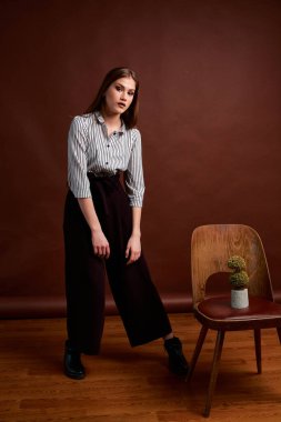 Genç bağımsız kadının mininalizm stili klasik stüdyo fotoğraf seti. Klasik takım elbiseli, siyah ayakkabılı ve gri ceketli güzel bir bayan. Klasik sandalye. Kadın kıyafetleri. Şık kıyafetler..