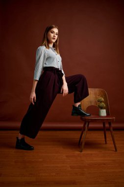 Genç bağımsız kadının mininalizm stili klasik stüdyo fotoğraf seti. Klasik takım elbiseli, siyah ayakkabılı ve gri ceketli güzel bir bayan. Klasik sandalye. Kadın kıyafetleri. Şık kıyafetler..