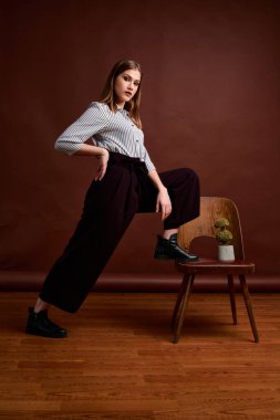 Genç bağımsız kadının mininalizm stili klasik stüdyo fotoğraf seti. Klasik takım elbiseli, siyah ayakkabılı ve gri ceketli güzel bir bayan. Klasik sandalye. Kadın kıyafetleri. Şık kıyafetler..