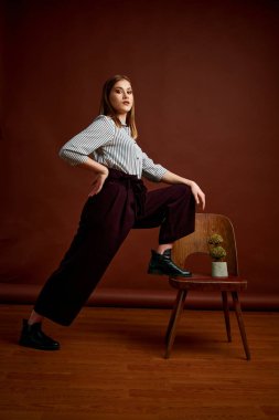 Genç bağımsız kadının mininalizm stili klasik stüdyo fotoğraf seti. Klasik takım elbiseli, siyah ayakkabılı ve gri ceketli güzel bir bayan. Klasik sandalye. Kadın kıyafetleri. Şık kıyafetler..