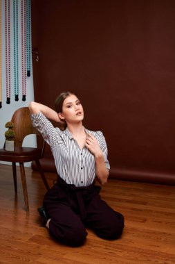 Genç bağımsız kadının minimalizm stili klasik stüdyo fotoğraf seti. Klasik takım elbiseli, siyah ayakkabılı ve gri ceketli güzel bir bayan. Klasik sandalye. Kadın kıyafetleri. Şık kıyafetler..