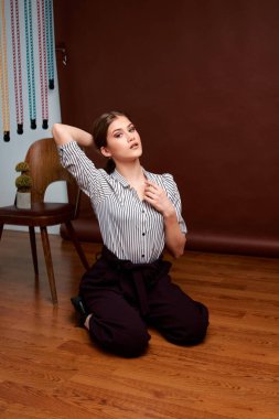 Genç bağımsız kadının minimalizm stili klasik stüdyo fotoğraf seti. Klasik takım elbiseli, siyah ayakkabılı ve gri ceketli güzel bir bayan. Klasik sandalye. Kadın kıyafetleri. Şık kıyafetler..