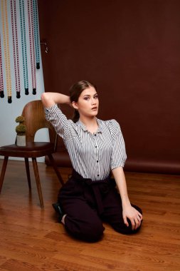 Genç bağımsız kadının minimalizm stili klasik stüdyo fotoğraf seti. Klasik takım elbiseli, siyah ayakkabılı ve gri ceketli güzel bir bayan. Klasik sandalye. Kadın kıyafetleri. Şık kıyafetler..